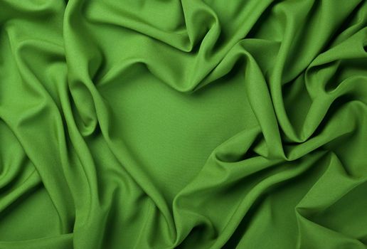 Close up abstract textile background of heart shaped green folded pleats of fabric, elevated top view, directly above