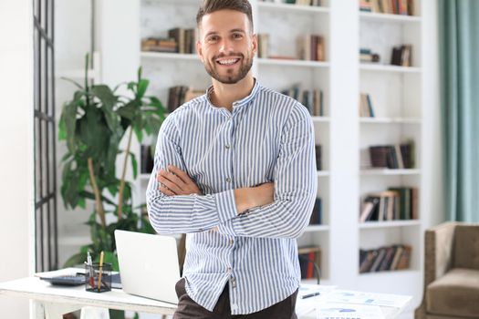 Portrait of happy businessman with arms crossed standing in office