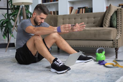 Handsome man doing sport exercise at home during quarantine. Concept of healthy life