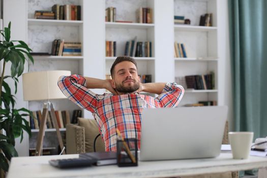 Smiling handsome businessman relaxing at home office