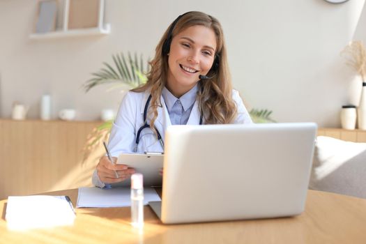 Concentrated doctor working online with a laptop sitting in a desk in a consultation