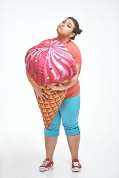 Funny picture of amusing, brunette, chubby woman on white background. Woman is holding a huge ice cream