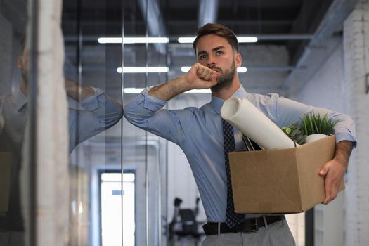 Sad dismissed worker is taking his office supplies with him from office