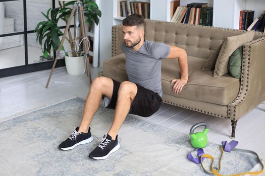 Handsome man doing sport exercise at home during quarantine. Concept of healthy life