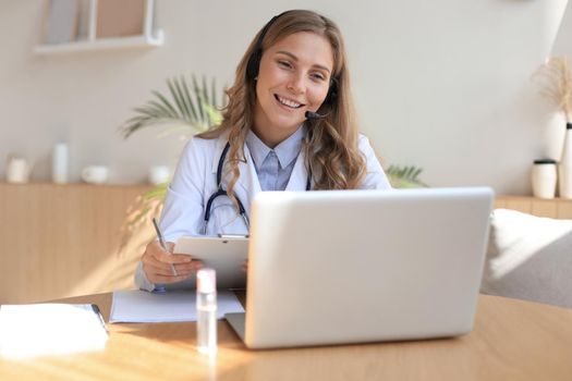 Concentrated doctor working online with a laptop sitting in a desk in a consultation