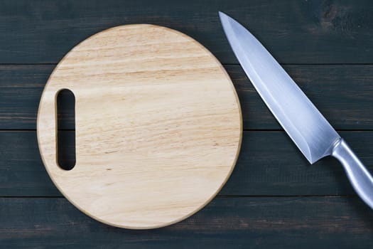 Close up kitchen knife and wooden round empty cutting board on a wooden table
