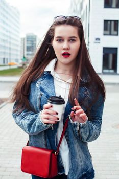 young pretty brunette business woman posing against modern building in glasses holding coffee, lifestyle people concept close up