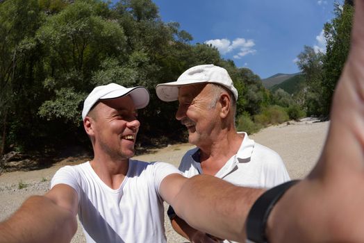 senior dad and son taking selfie photos on  hiking tour