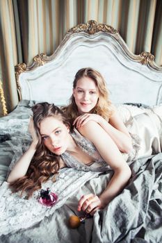 two pretty twin sister blond curly hairstyle girl in luxury house interior together, rich young people concept close up