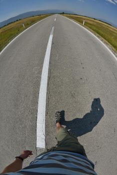 pov view of man walking in alone on country road at sunny summer day