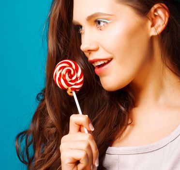 young pretty adorable brunette woman with curly hair close up like doll makeup on blue background, posing emotional, lifestyle people concept