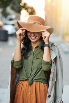 Playful beauty. Young happy caucasian woman adjusting hat and smiling while standing on the city street, enjoying walking on warm autumn day. Beautiful people concept