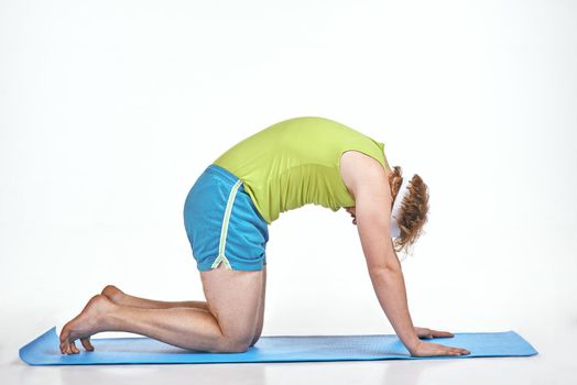 Funny picture of amusing, red haired, chubby man on white background. Man trains on the mat.