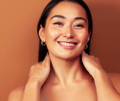 young pretty asian woman cheerful smiling posing on warm brown background, lifestyle people concept close up