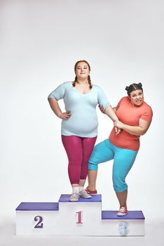 Overweight women are standing on a winner's pedestal isolated on white background and argue
