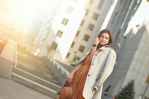 Young beautiful and stylish caucasian woman wearing long romantic dress looking aside and thinking about something while standing on the city street, walking outdoors