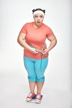 Picture of chubby woman on white background. Woman is measuring her belly