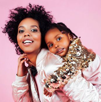 young pretty african-american mother with little cute daughter hugging, happy smiling on pink background, lifestyle modern people concept close up