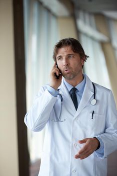 handsome doctor speaking on cellphone at modern hospital indoors