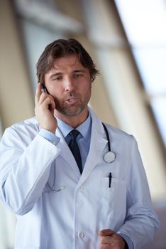 handsome doctor speaking on cellphone at modern hospital indoors