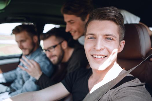 Side view of cheerful senior man in formal wear sitting in car and looking over shoulder