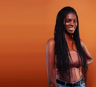 pretty young african american woman with braids posing cheerful gesturing on brown background, lifestyle people concept close up