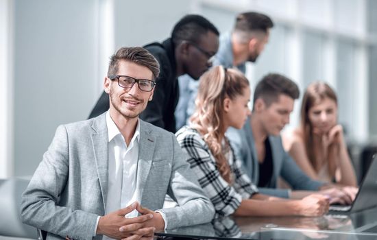 Male boss addressing meeting around boardroom table