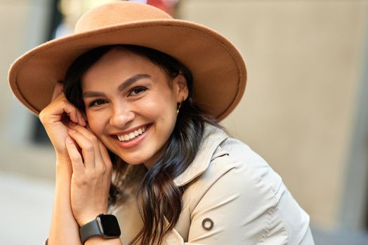 Portrait of a young cute happy woman wearing hat looking at camera and smiling while spending time outdoors. People lifestyle concept