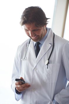 handsome doctor speaking on cellphone at modern hospital indoors