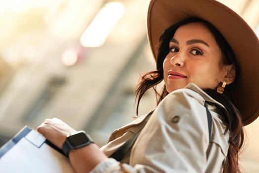 Portrait of a stylish beautiful caucasian woman wearing hat looking at camera while walking city streets. Fashion, people lifestyle concept