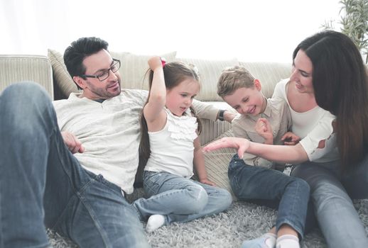 parents play with children sitting on the carpet in the living room.happy family concept