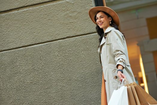 Visiting fashion boutique. Young happy fashionable woman wearing grey autumn coat and hat with shopping bags walking city streets and smiling. People lifestyle concept