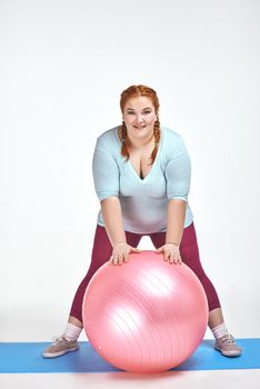 Funny picture of amusing, red haired, chubby woman on white background. Woman holding a ball