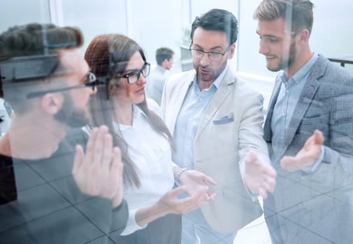 smiling employees discuss new ideas standing in the office.the concept of teamwork