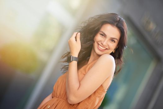 Portrait of a young happy attractive caucasian woman wearing summer dress looking at camera and smiling while standing on the city street. Beautiful people concept