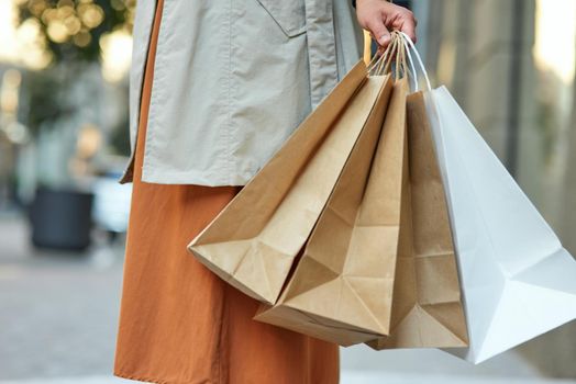 Cropped shot of a woman with shopping bags standing on city street. People lifestyle concept