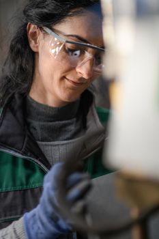 Woman worker wearing safety goggles control lathe machines to drill components. Metal lathe industrial manufacturing factory. High quality photo