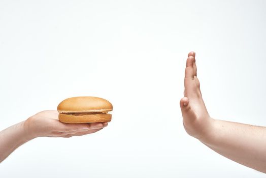 In picture one person offers sandwich another, but the person refuses.