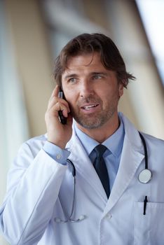 handsome doctor speaking on cellphone at modern hospital indoors