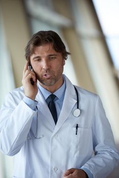 handsome doctor speaking on cellphone at modern hospital indoors