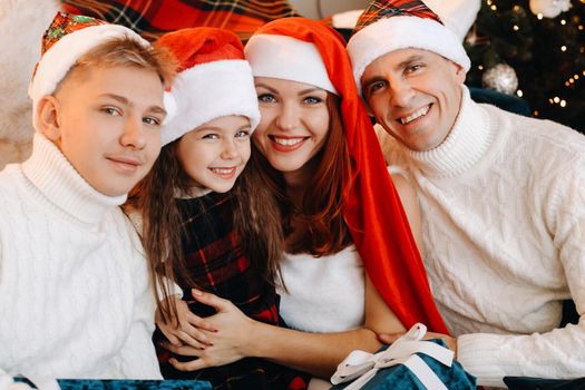 Close-up portrait of a happy family sitting on a sofa near a Christmas tree celebrating a holiday.