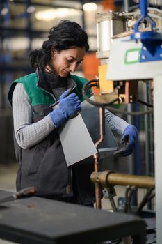 a woman working in a modern metal factory assembles parts for a new machine. High quality photo