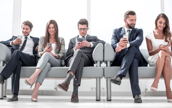 business colleagues with their smartphones sitting in the office hallway.people and technology