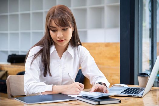 Cheerful young asian woman using laptop computer at home. Student female in living room. online learning, studying , online shopping, freelance, asean concept