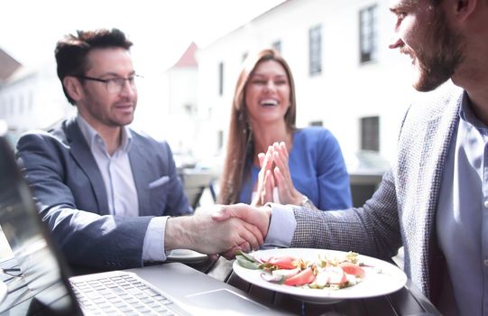 colleagues greeting each other with a handshake in the cafe.business concept