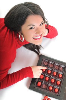 young beautiful brunette woman in red isolated on white eat chocolate food