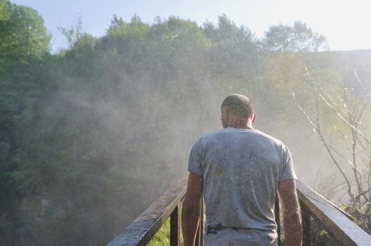 standing man with wide opened arms with waterfalls in background and representing freshness healthy lifestyle and success concept