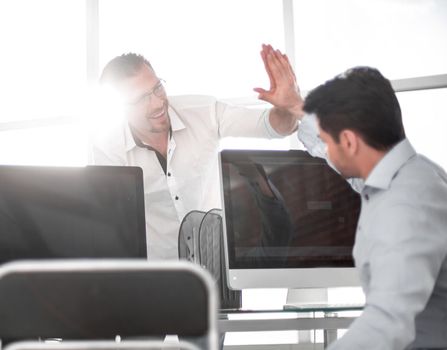 employees give each other a high five over the computer Desk. success concept