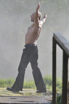 standing man with wide opened arms with waterfalls in background and representing freshness healthy lifestyle and success concept