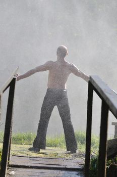 standing man with wide opened arms with waterfalls in background and representing freshness healthy lifestyle and success concept